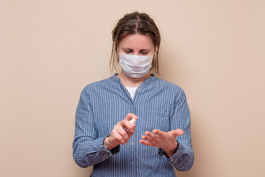 Young woman spraying her hands with sanitizer protecting herself from virus.