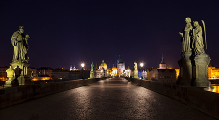 Fototapeta na wymiar Night colorful Prague Old Town with Bridge Tower and St. Francis of Assisi Cathedral from Charles Bridge with its baroque Statues without People at the time of Coronavirus, Czech republic