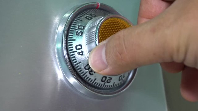 Man hand Opening old safe combination lock turning dials.