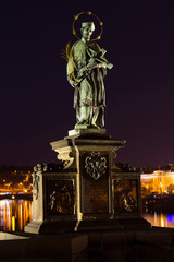 Jan Nepomucky, St. John of Nepomuk, the most famous Czech saint, tortured by King Vaclav , . - his Statue on Prague Charles Bridge in the Night without People at the time of Coronavirus, Czechia