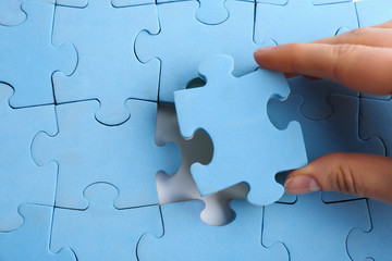 Fototapeta premium Woman putting light blue puzzle together, closeup. Career promotion concept