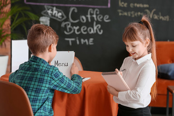 Cute little waiter serving client in restaurant