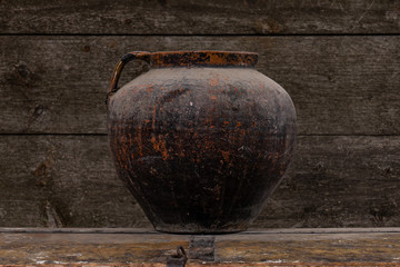 Photo of an empty clay vase on aged rustic wooden table, retro wooden wall