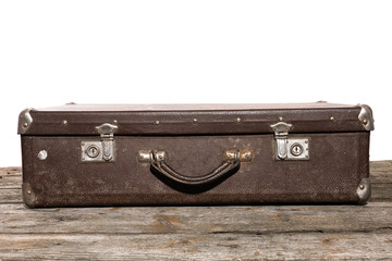 Old brown suitcase for travel lyies on the wooden table