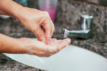 Woman washing her hands with soap and water at the bathroom sink. Coronavirus and Covid-19 prevention