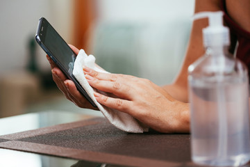 Obraz premium Cleaning smartphone to prevent coronavirus contamination. Precaution against Covid-19