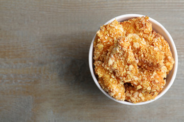 Bucket with yummy nuggets on wooden table, top view. Space for text