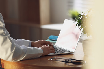 Professional doctor working on laptop in office, closeup