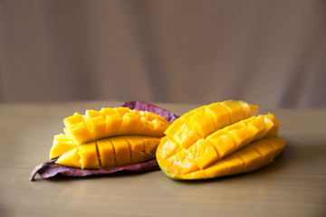 Mango cut into slices on a leaf on a beige background