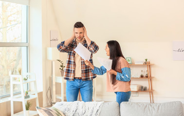 Displeased woman scolding her husband for overspending at home
