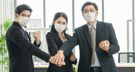 A team of business men and women working together and wearing protective masks