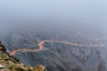 Long exposure of car light trails on a foggy mountain road at Al Huda, Saudi Arabia