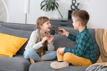 Cute little children eating chocolate at home