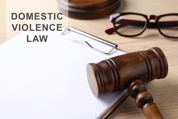 Clipboard and gavel on wooden table. Domestic violence law concept