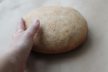 Fototapeta na wymiar A woman's hand reaches for the freshly baked bread. The concept of cooking delicious and healthy food at home.