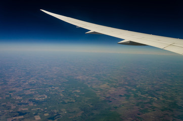 Aerial view of the earth from an airplane window showing the planes wing 