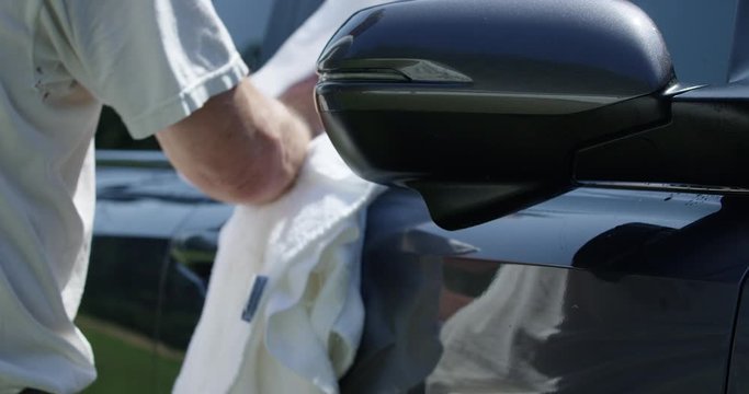 Older Man Drying His Car With A Towel After Washing It On A Summer Weekend - Close Up On Towel Drying Side Windows