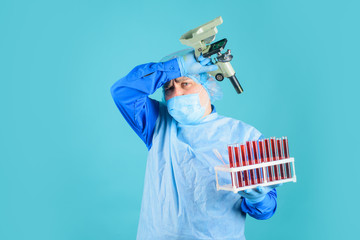 Doctor analyzing blood sample. Tired doctor with test tubes and microscope. Science, biology and...