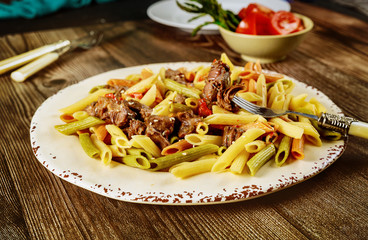 Penne pasta with beef and bolognese sauce and vegetable in plate with fork.