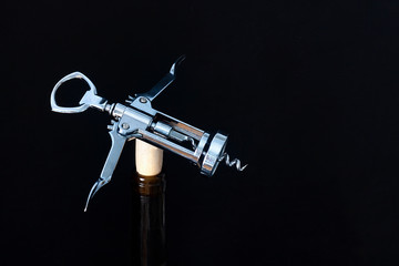Naklejka premium CORKSCREW ON WINE BOTTLE AND BLACK BACKGROUND