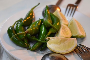 Sliced lemons and green peppers on a restaurant table served together with kebab