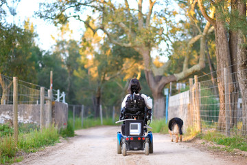A disabled woman walking around with her dog in the park