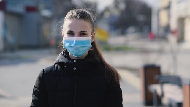 Girl in protective mask and gloves using smartphone outdoors. COVID 19. World coronavirus pandemic.