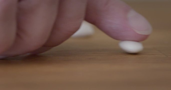Fingers push in a single bean, remove it, then count out five white beans on wooden table top, metaphor for bean counting accountants. Macro with shallow focus 4K.