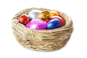 Nest with sweet chocolate eggs on white background