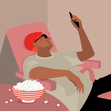 Man sitting in a lounge chair watching his phone next to a bowl of popcorn.