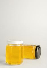 Jars of sweet honey on light background