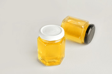 Jars of sweet honey on light background