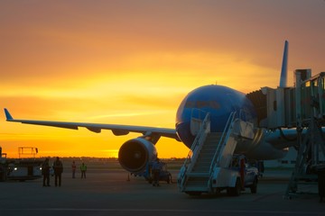 Fototapeta na wymiar Airport ground crew loading cargo and luggage on a commercial aircraft at dawn.