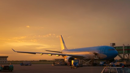 Airport ground crew loading cargo and luggage on a commercial aircraft at dawn.