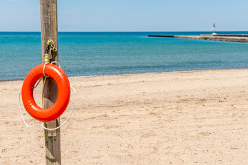 life belt, life saver hung on wooden pole on beach, foreground focused.
