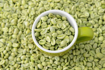 Cup on green coffee beans