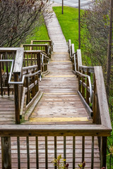 Large wooden staircase with  hand rail leading down into a park, springtime