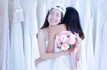 Fototapeta na wymiar Asian brides happily hug the brides on the wedding day while holding flowers