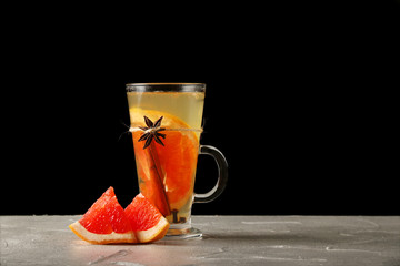 hot beverage with grapefruit in a mulled wine glass on black background. hot beverage concept