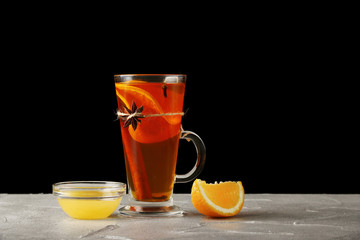 hot beverage with orange and honey in a mulled wine glass on black background. groge in glass isolated on black. hot beverage concept