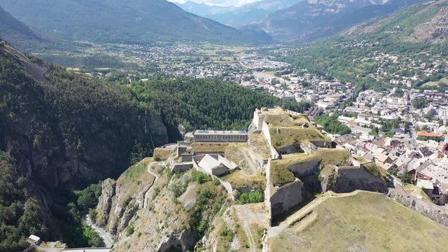 Picturesque autumn landscape with imposing medieval citadel on hilltop on background with French fortified township of Briancon