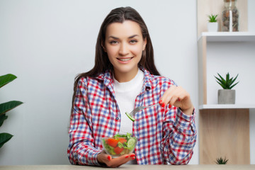 Cute woman eats vegetable salad with lots of vitamins.