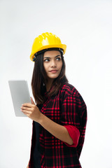 The young woman engineer with yellow safety helmet holding taplet in hand,turn face to left side for looikng something