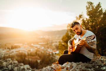 Young man holding acoustic guitar and looking to sunset.Searching inspiration.Music creator.New artist.Musical talent.Handsome guitarist enjoying sunset and playing acoustic guitar.