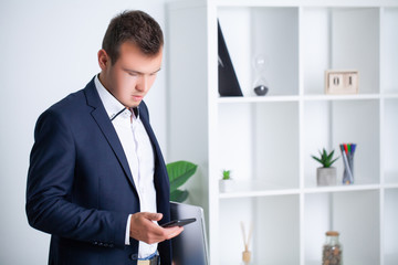 Handsome young worker uses a telephone in the company office