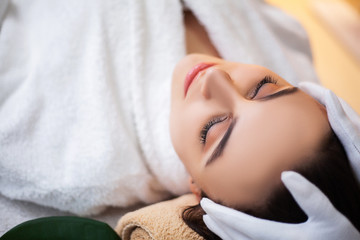 Fototapeta na wymiar Pretty woman receiving facial massage in spa salon