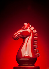 Wooden chess knight in red with red background