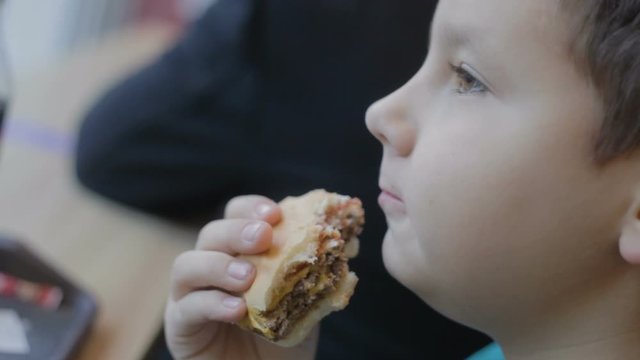 hungry teenager eats junk food. Close-up. Burger, cheeseburger, sandwich