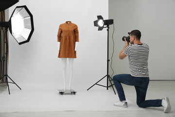 Professional photographer taking picture of ghost mannequin with stylish clothes in modern photo