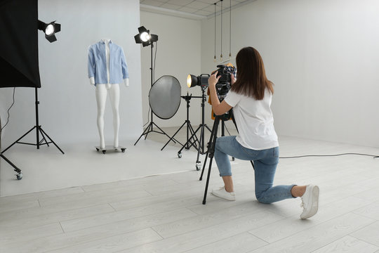 Professional photographer taking picture of ghost mannequin with modern clothes in photo studio